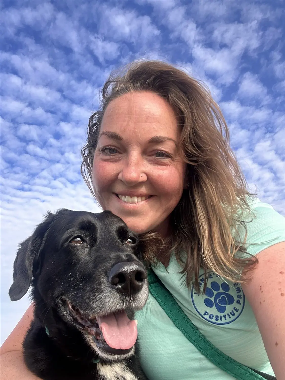 Jennie from Jennie's Positive Paws smiling outdoors with a dog