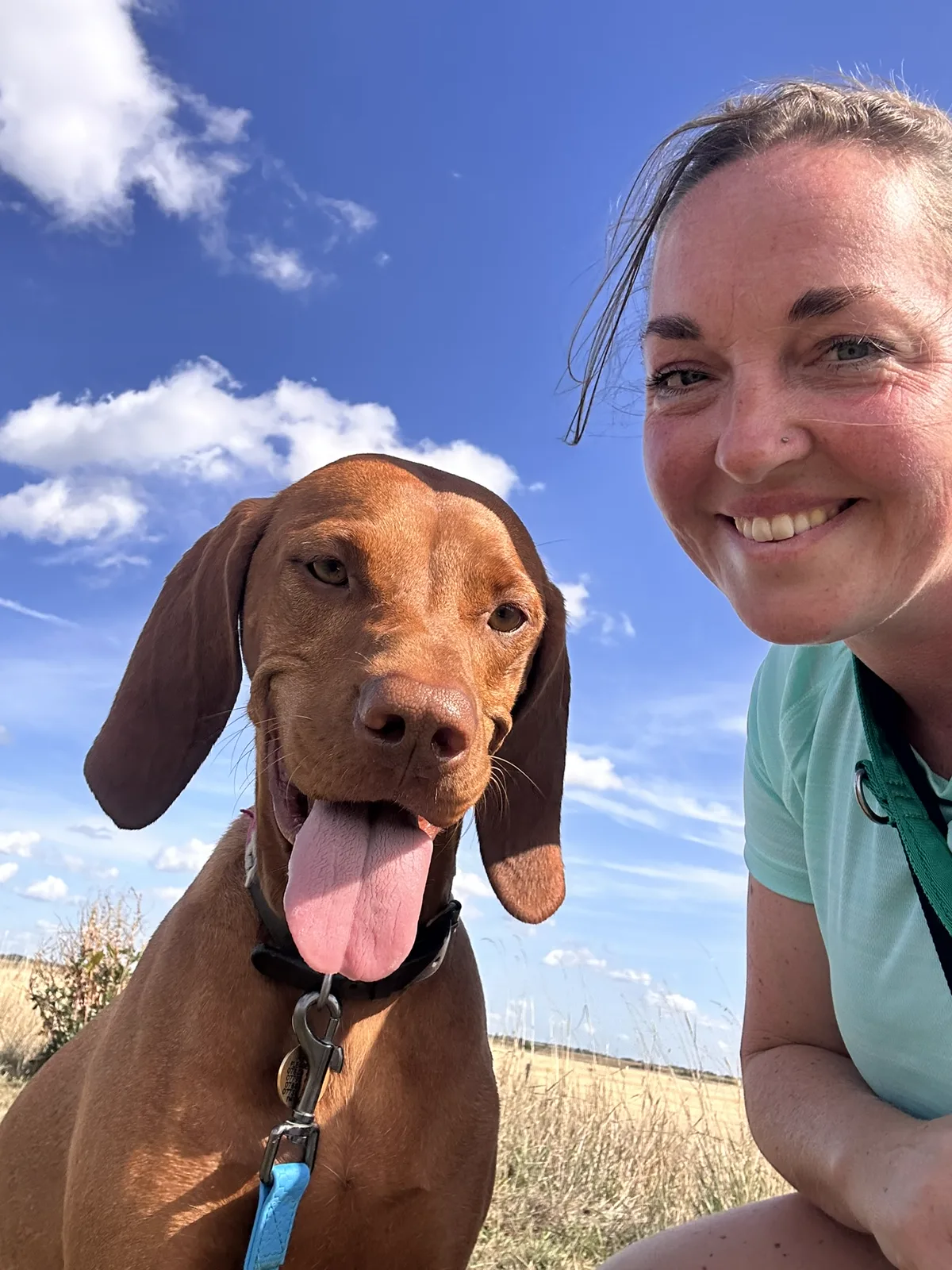 Jennie from Jennie's Positive Paws smiling outdoors with a Vizsla
