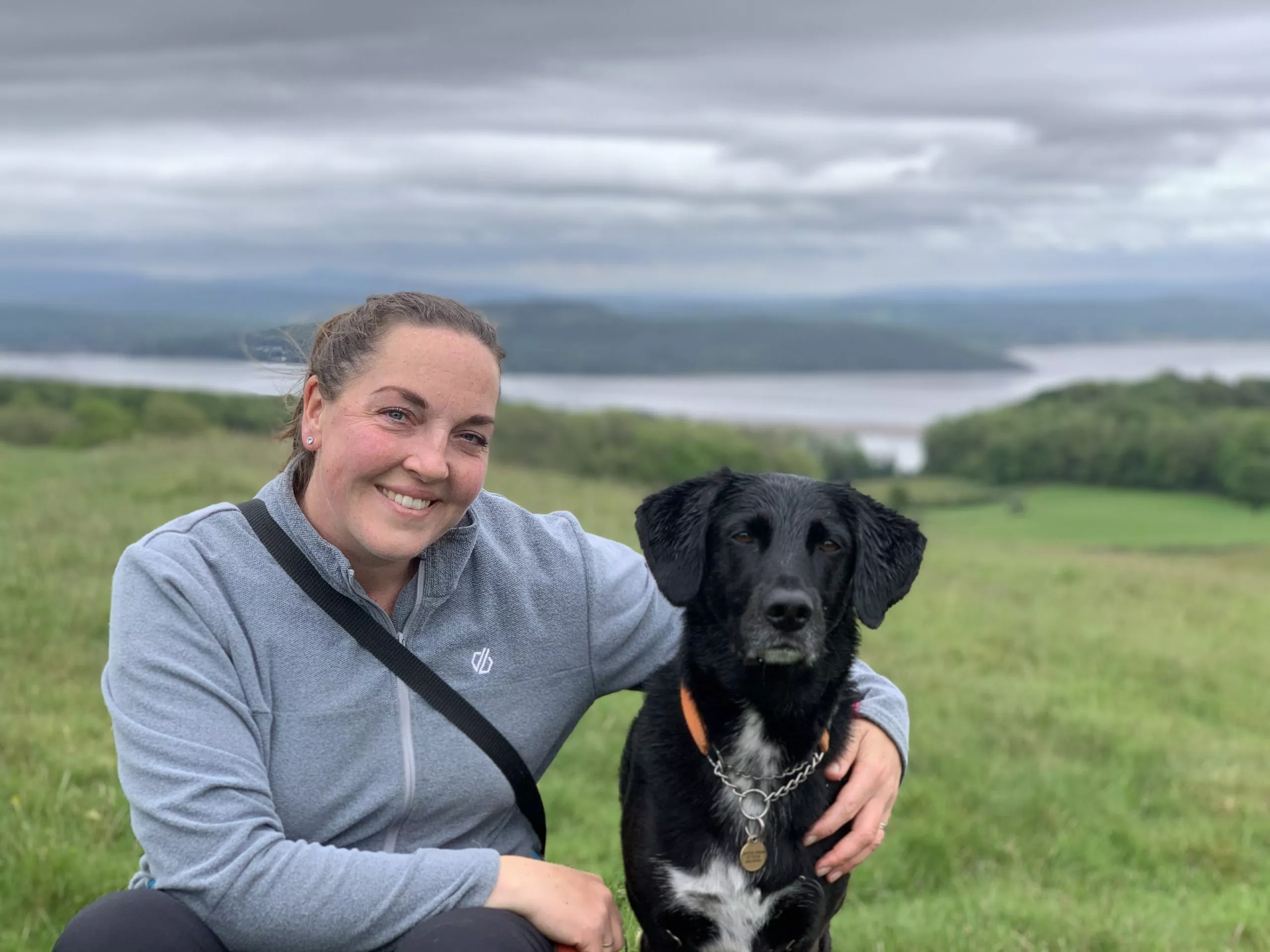 Jennie sitting with a dog outdoors during a calm training moment